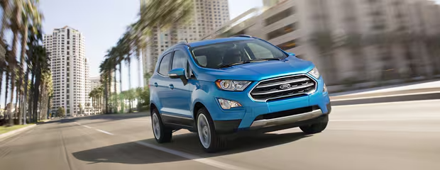 A blue SUV speeds down a palm-lined city street, conveying motion and excitement. Tall buildings blur in the background, suggesting urban energy.