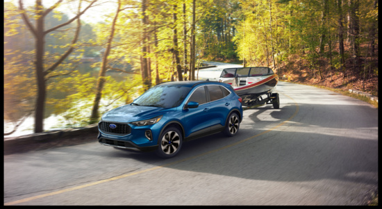 A blue SUV tows a boat on a winding road beside a serene lake, surrounded by lush autumn trees. The scene conveys a sense of adventure and tranquility.