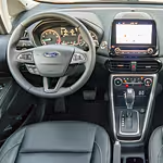 Interior of a modern car showing a sleek dashboard with a digital display, steering wheel, and central console with controls, conveying a tech-savvy design.