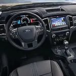 A modern car interior featuring a sleek dashboard with a multifunction steering wheel, digital speedometer, and infotainment screen displaying apps.