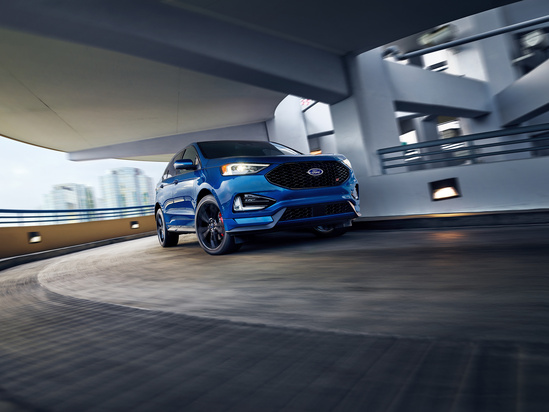 A blue SUV drives through an urban parking structure, conveying motion and modernity. The blurred background suggests speed and a dynamic city environment.