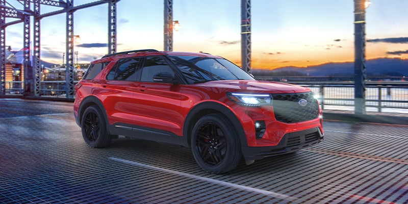 Red Ford SUV on bridge at sunset with city background